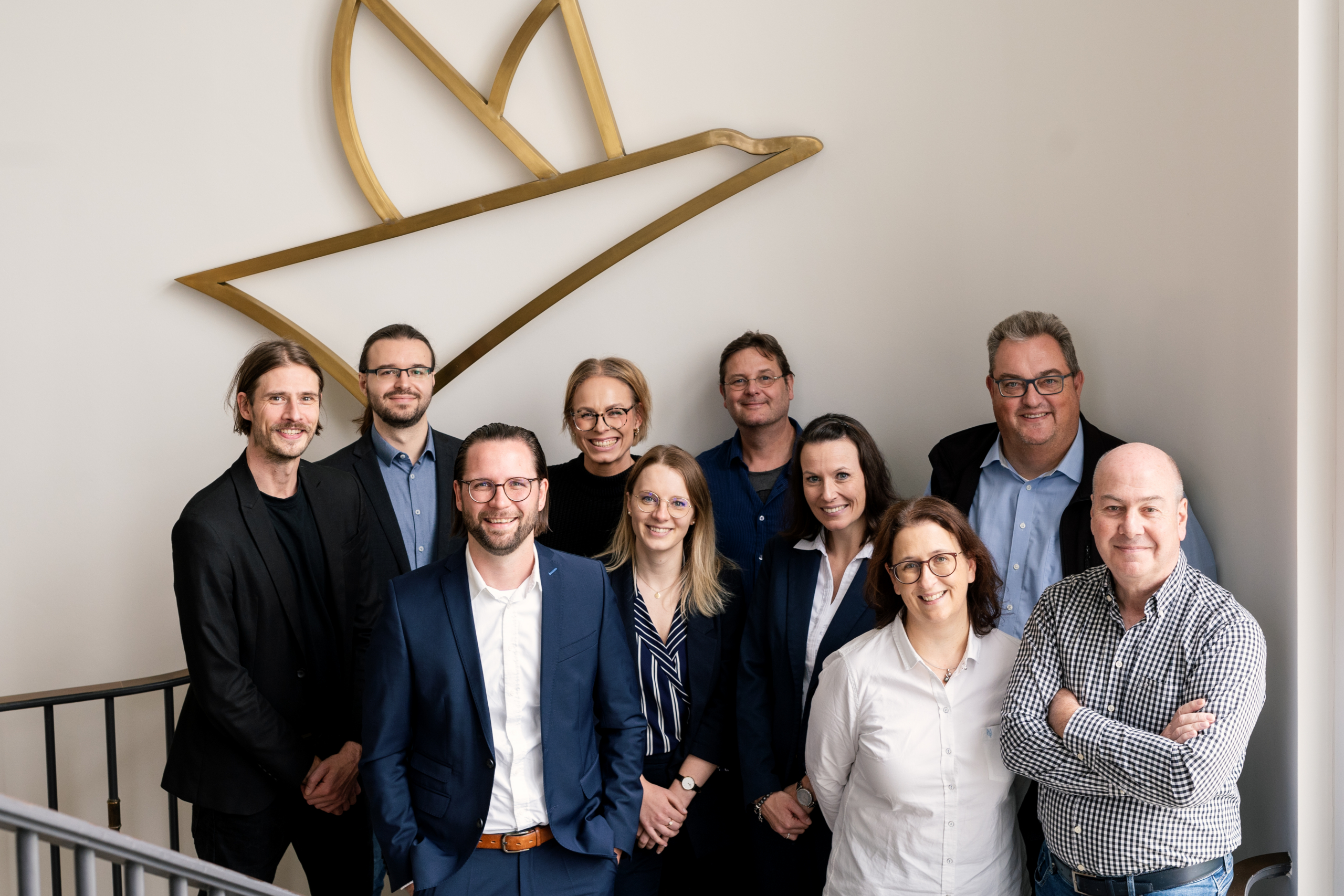 Gruppe von neun Personen in Businesskleidung vor einer Wand mit einem großem VOGEL-Logo